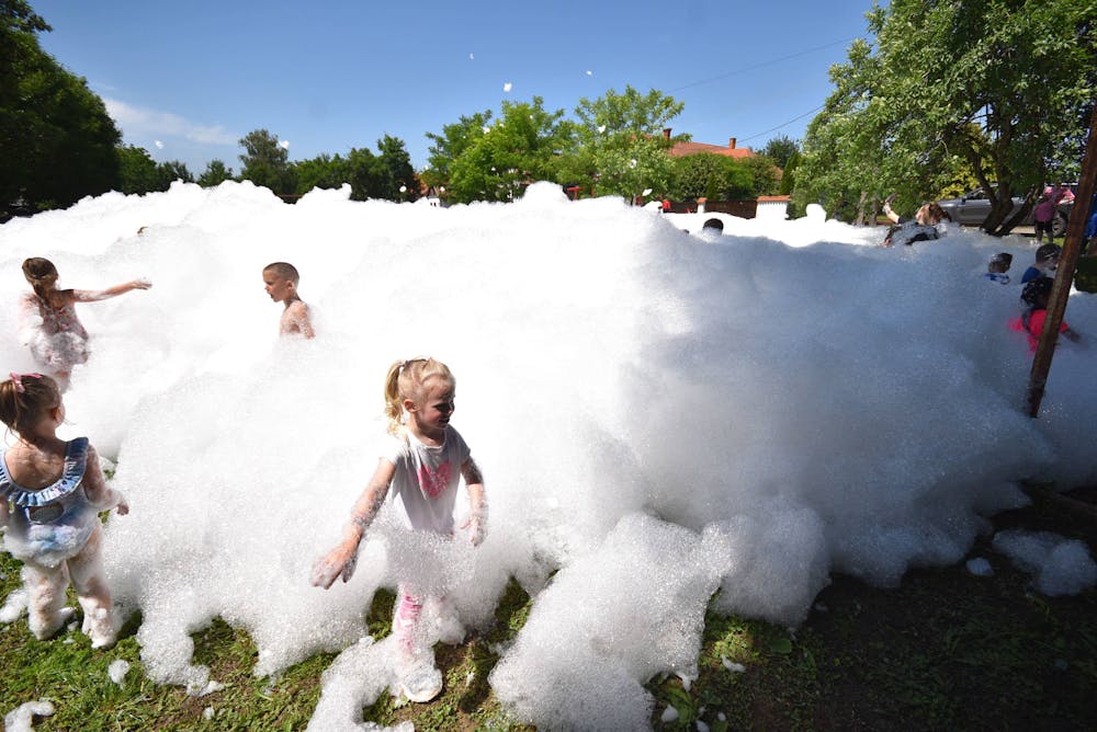 Children playing in white foam at a Miami kids foam party