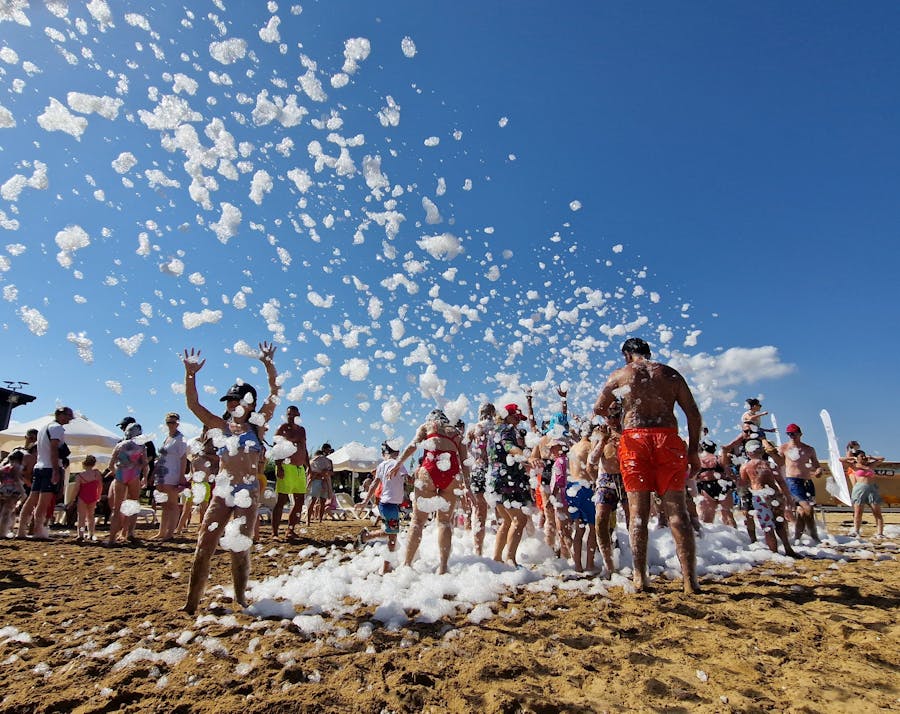 Crowd at a beach foam party with foam flying in the air
