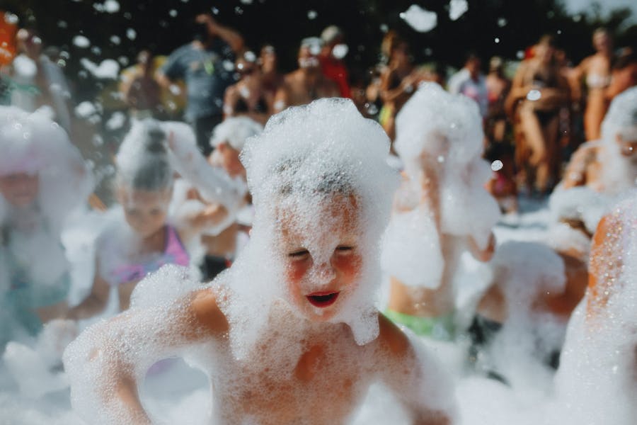 Child covered in foam at an outdoor foam party